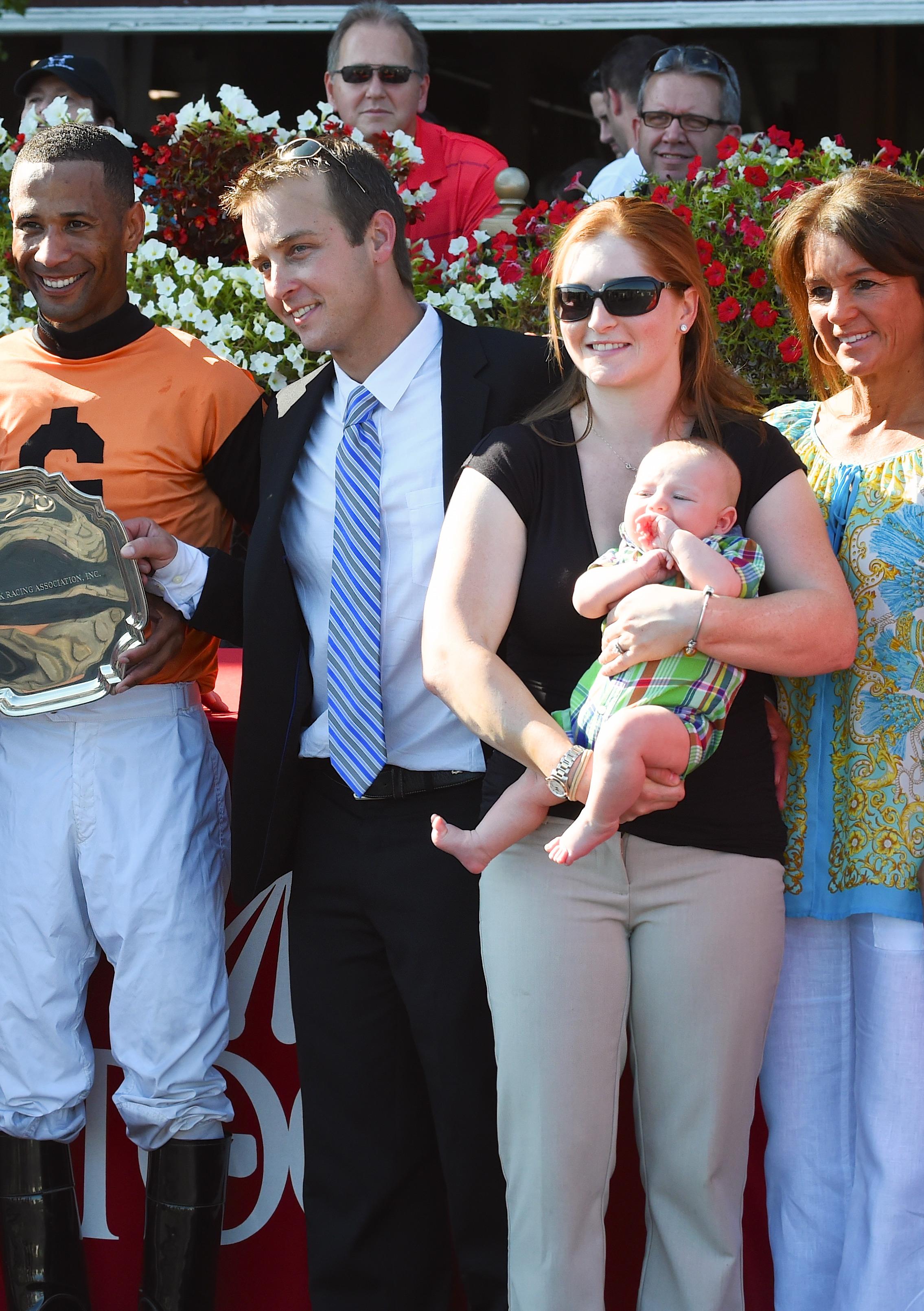 Rosie Napravnik, husband Joe Sharp, and son Carson in the Saratoga winner's circle.